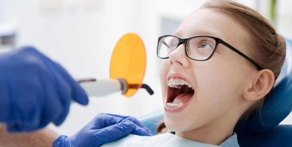 A young person wearing glasses having their fixed braces examined