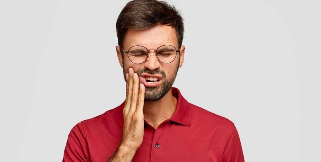 Man holding his cheek because of tooth pain