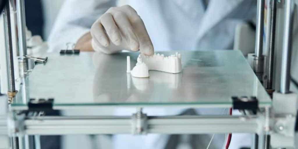 Gloved hand handling dental models on a machine platform