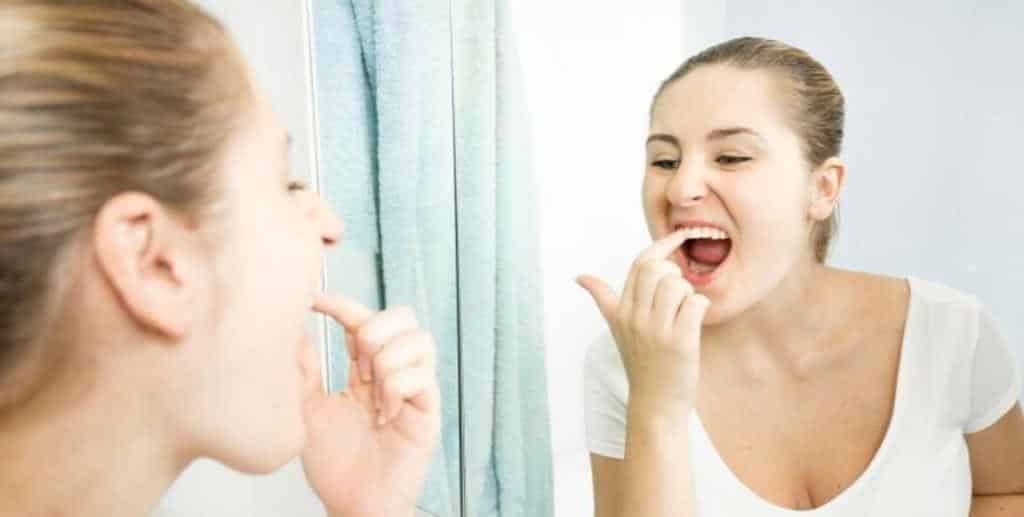 Person examining their teeth and gums in a mirror