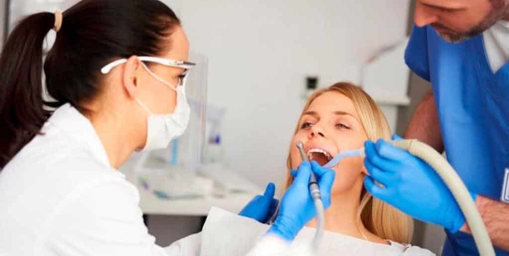 A dental team treating a patient in a dental chair