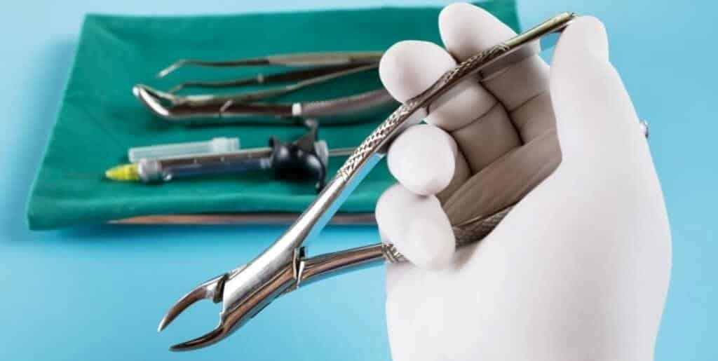 A gloved hand holding dental extraction forceps