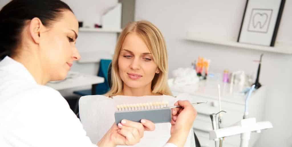 A patient looking at a tooth shade guide