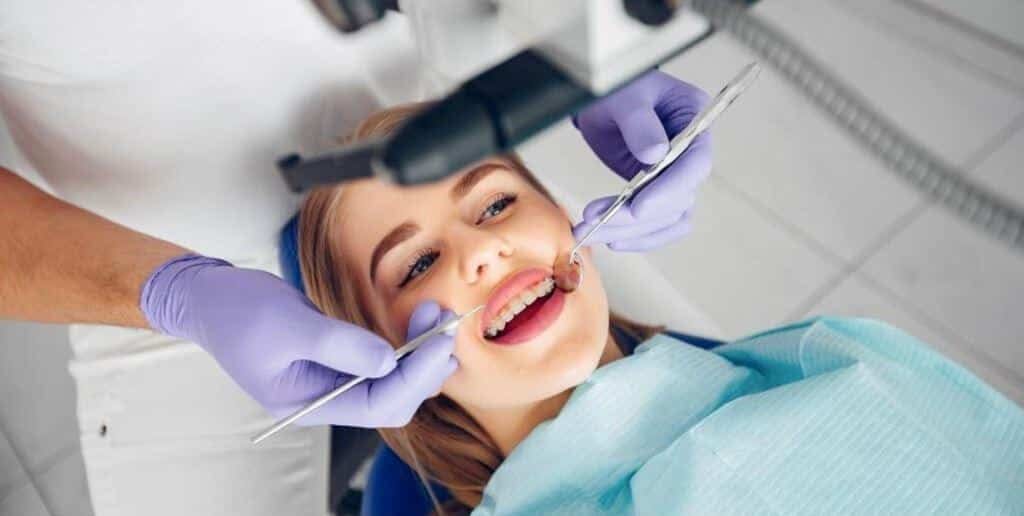 A patient having her teeth examined with a mirror and dental instrument