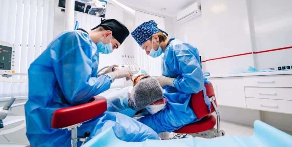 Two clinicians treating a patient in a dental chair