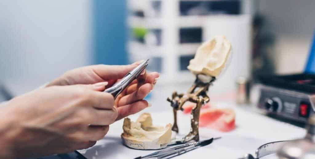Hands working with dental models and instruments
