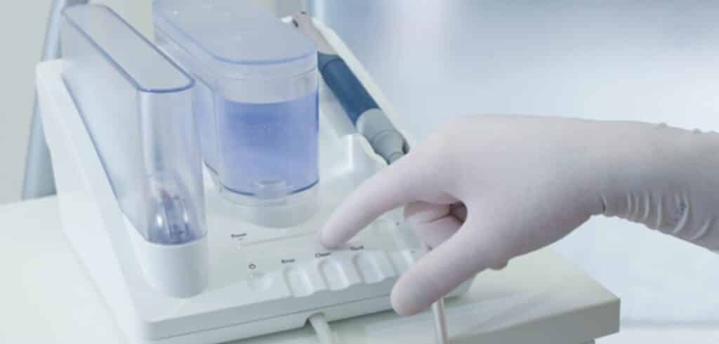 A gloved hand adjusting controls on dental equipment