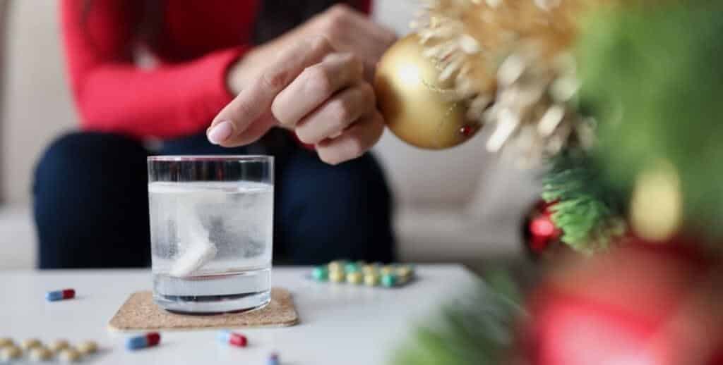 A tablet dissolving in a glass beside Christmas decorations