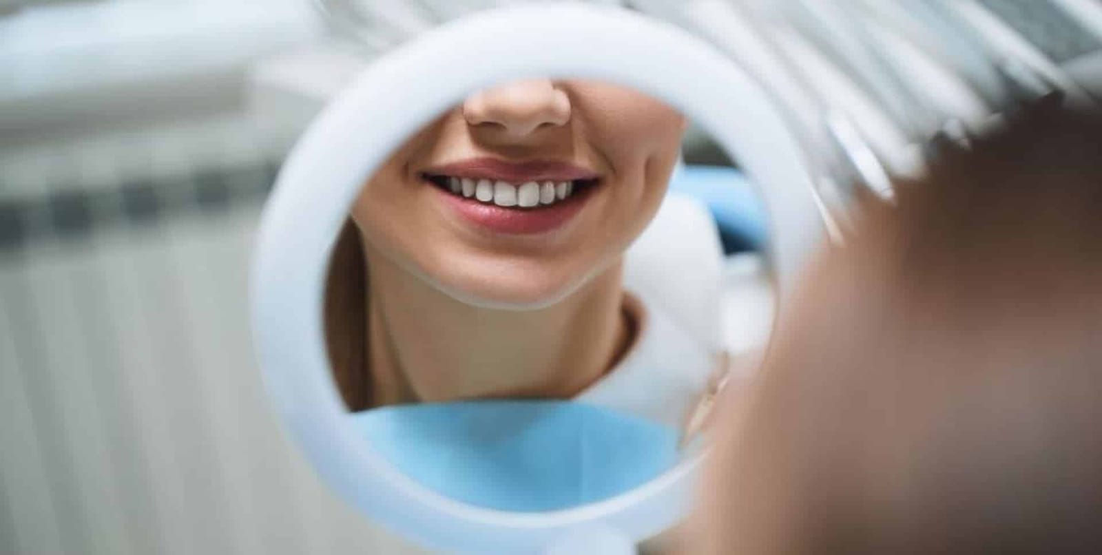 A patient’s smile reflected in a handheld mirror