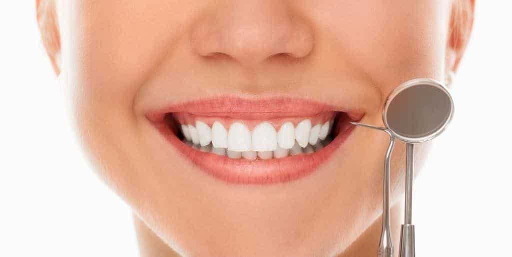 A smiling mouth beside a dental mirror