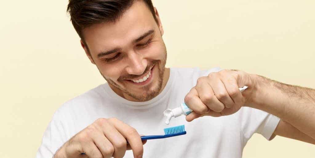 A man putting toothpaste on his toothbrush