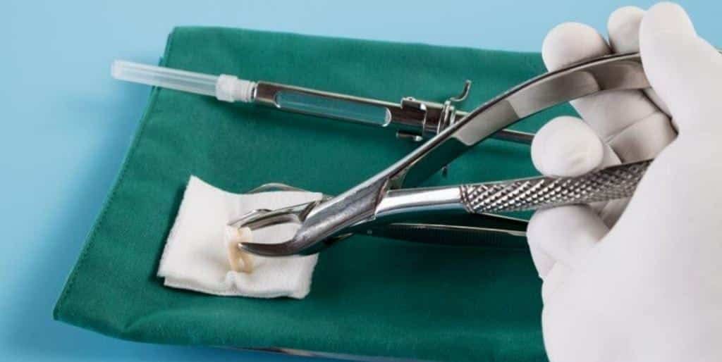Dental instruments and a syringe on a green cloth