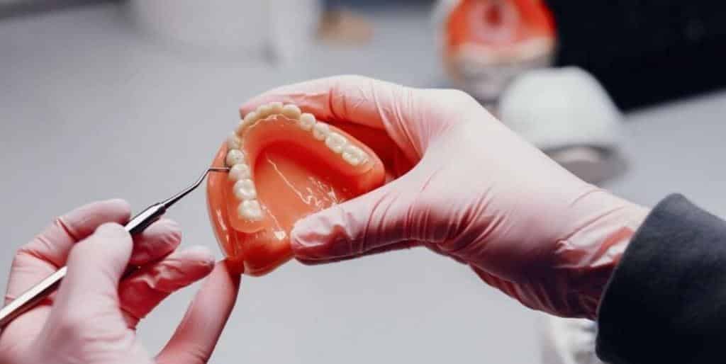 Gloved hands working on a removable denture