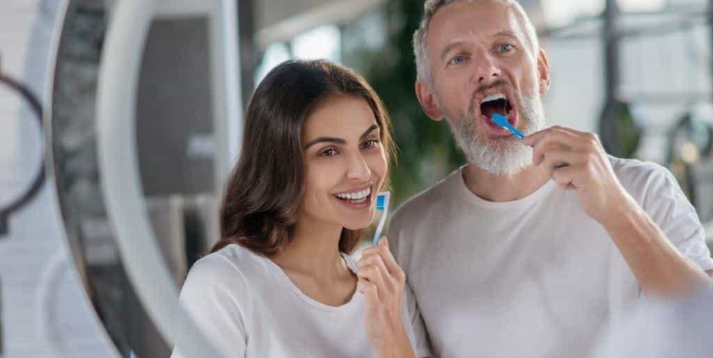 Two adults brushing their teeth