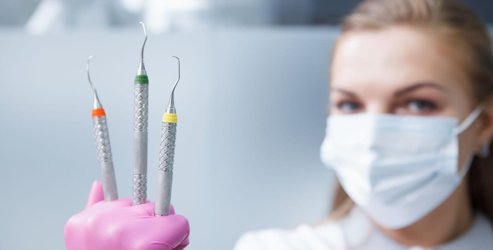 Small dental instruments held in a gloved hand