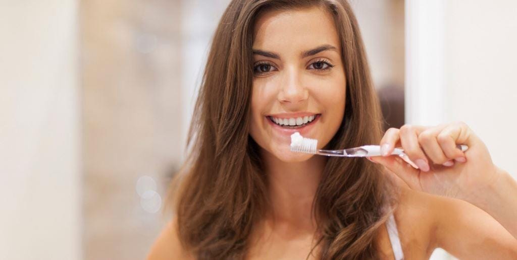 A person holding a toothbrush beside their smile