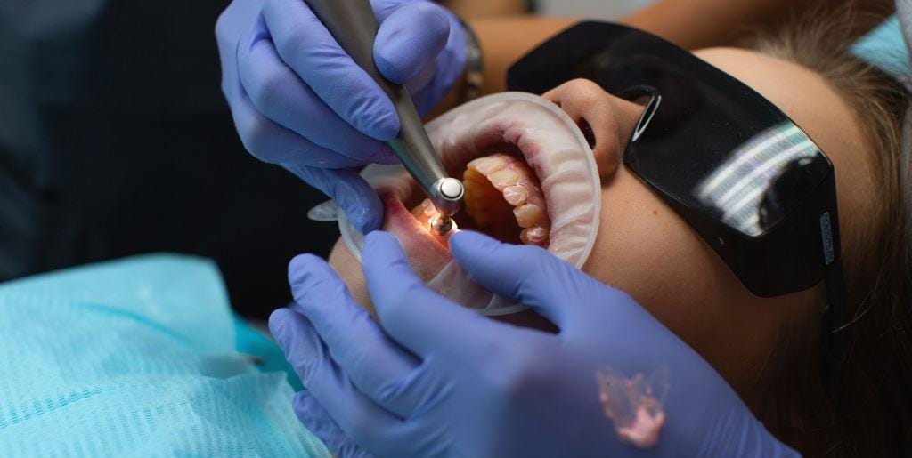 A clinician using instruments inside a patient’s mouth