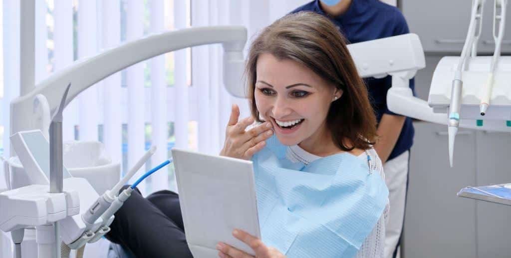 Patient looking at her teeth in a mirror after an appointment