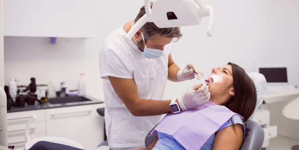 A clinician examining a patient in a dental chair