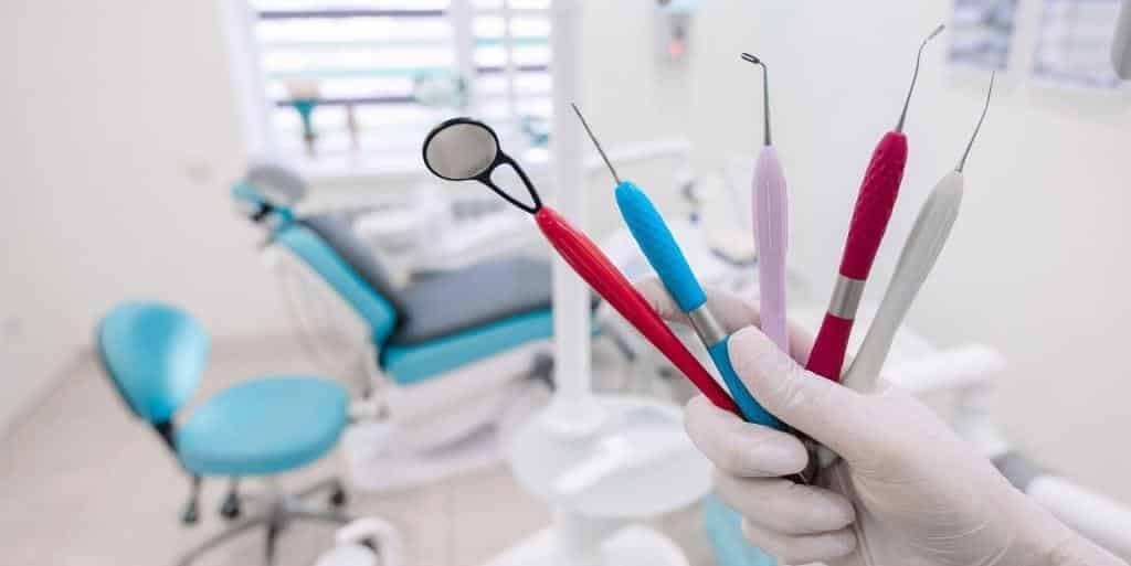 Dental instruments held in a gloved hand