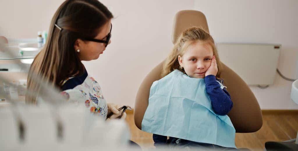 Dentist talking with a child in a treatment chair