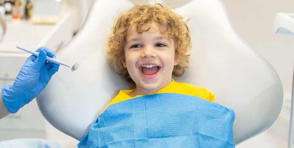 Child smiling while seated in a dental chair