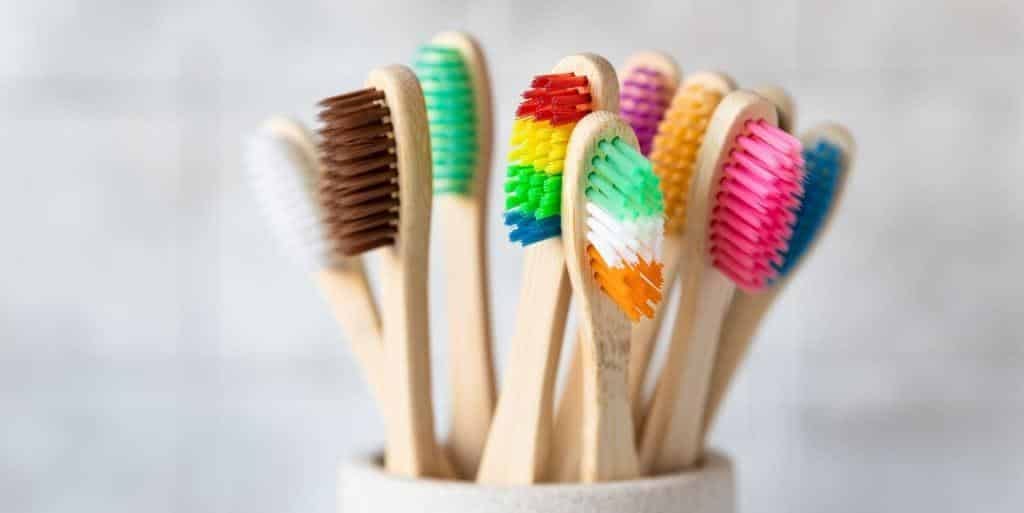 Wooden-handled toothbrushes with colourful bristles in a holder