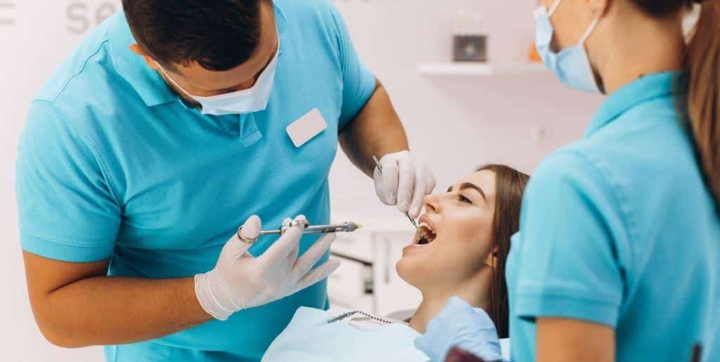 A dental team treating a patient in the dental chair