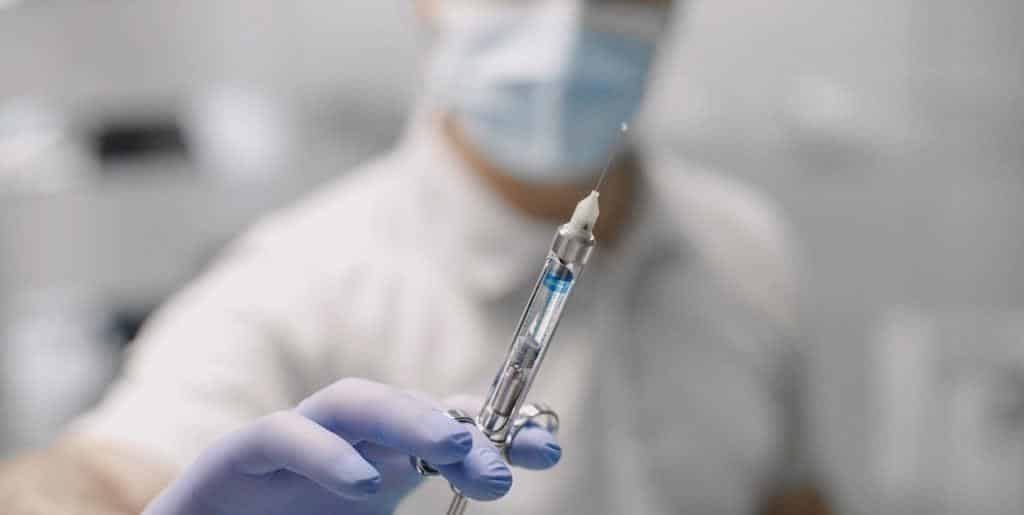 A dental syringe held in a gloved hand
