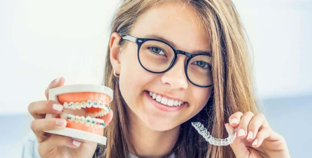 A person holding a dental model and a clear aligner