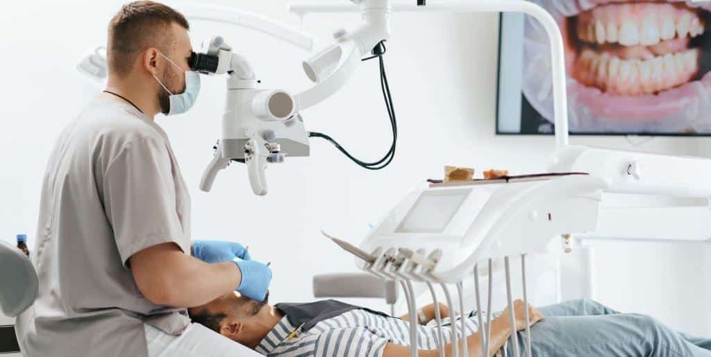 A dentist using a microscope while treating a patient