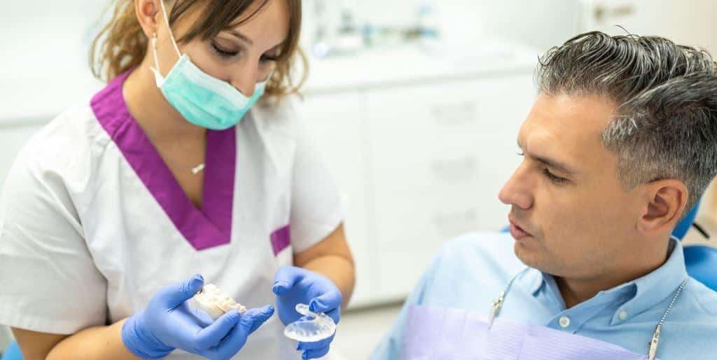 A clinician showing a patient a dental model and a clear appliance
