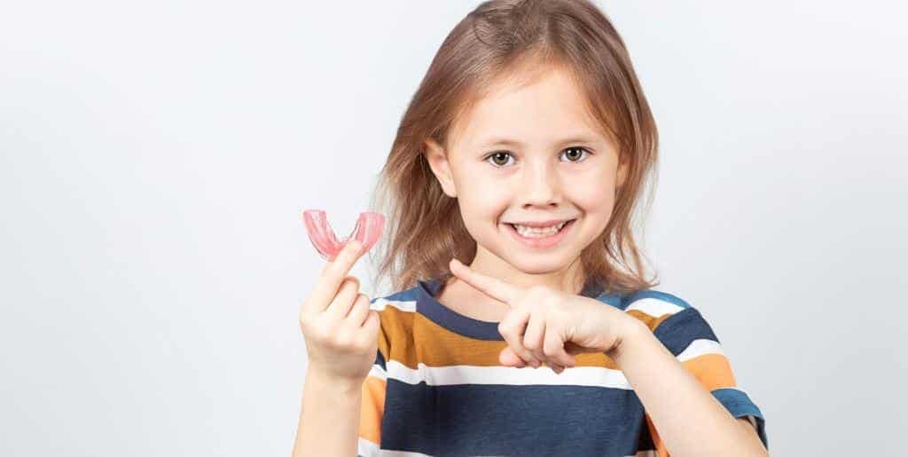 Child holding a toothbrush and a dental model