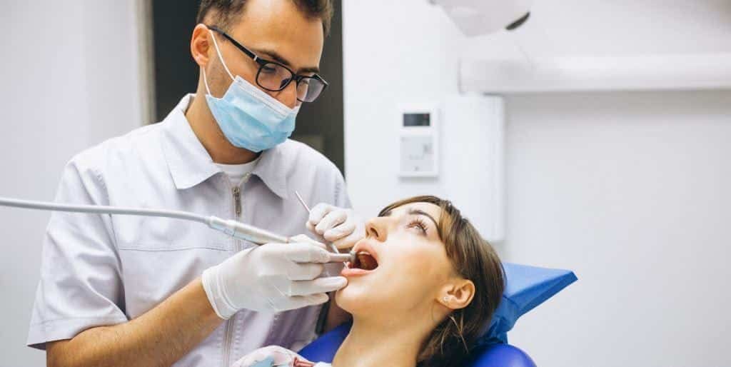 A masked clinician examining a patient