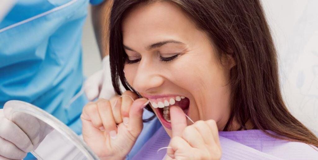 A person using dental floss between their teeth
