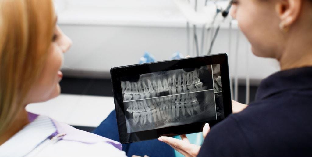 Patient and clinician looking at a dental X-ray on a tablet