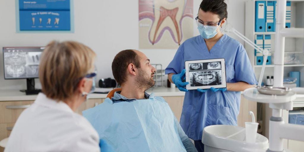 Clinician showing dental X-rays to a seated patient