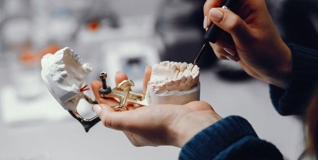 Hands working on a dental model in an articulator