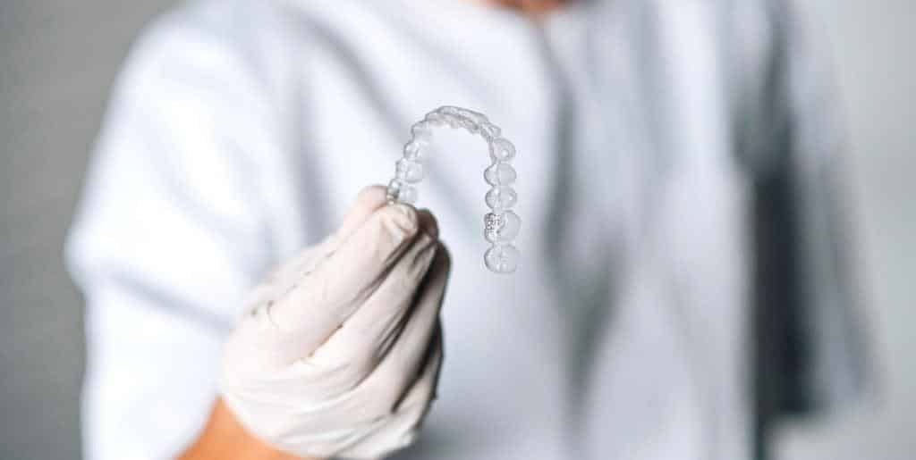 A gloved hand holding a clear dental tray