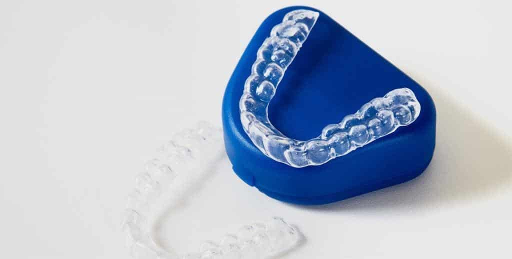 A clear dental tray resting on a blue case