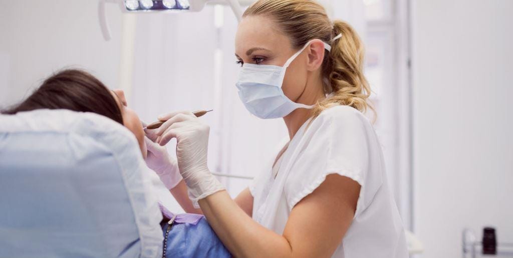 A clinician examining a patient in a dental chair