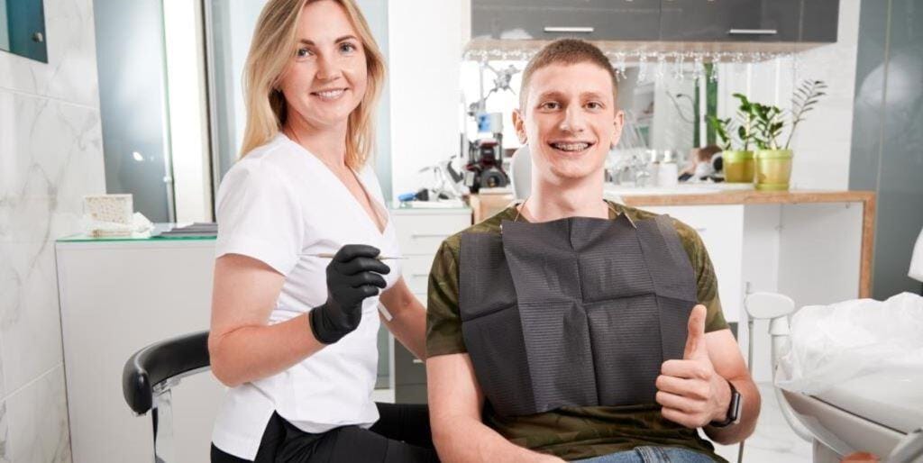 A patient and a dental team member beside a dental chair
