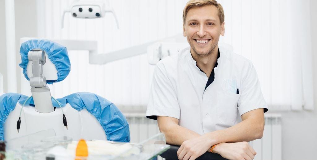 A dental professional seated beside a dental chair