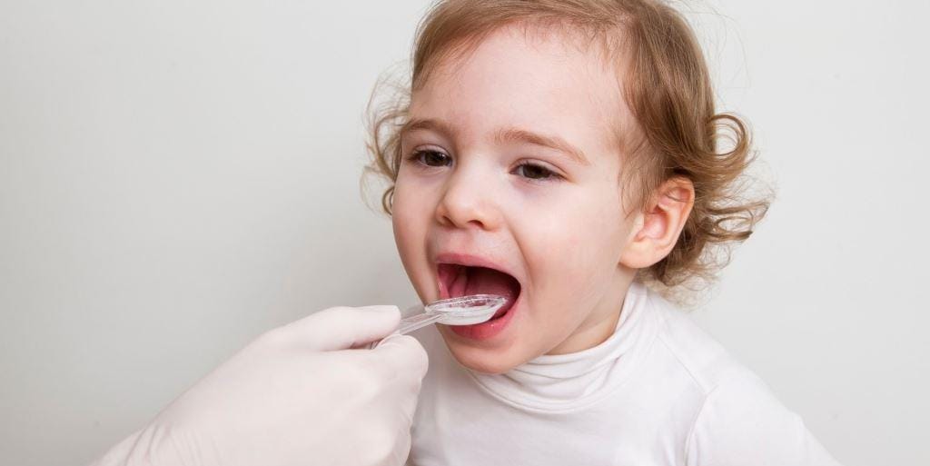 Young child having their teeth brushed by an adult