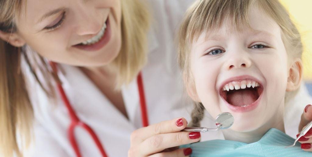 Dentist examining a child’s teeth with a dental mirror