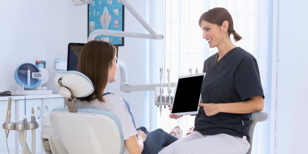 A clinician holding a tablet while speaking with a patient