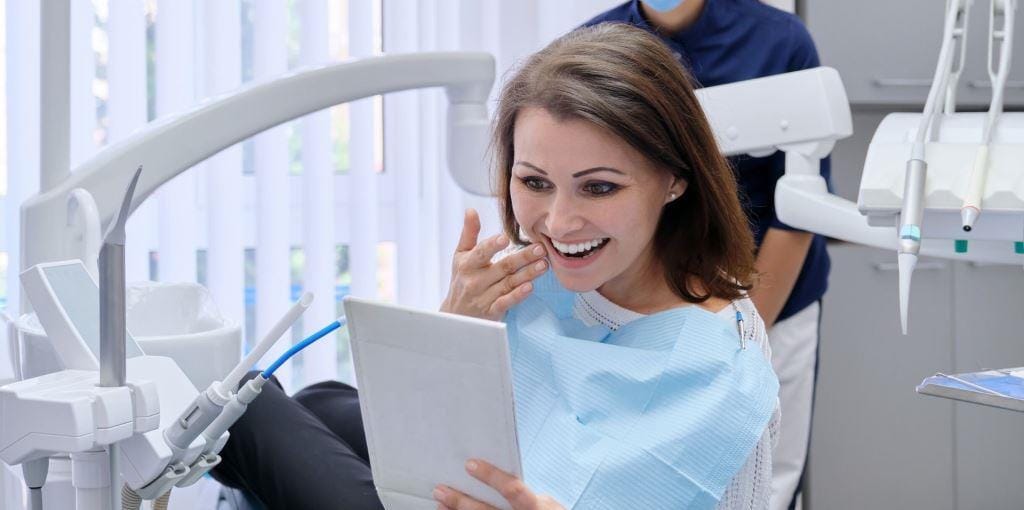 A smiling patient looking in a mirror