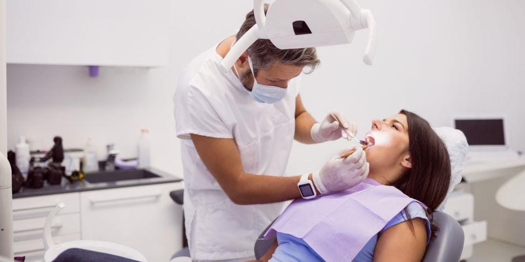 A clinician examining a patient in a dental chair