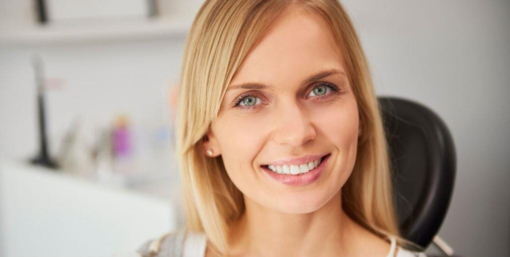 A woman smiling while seated in a dental chair