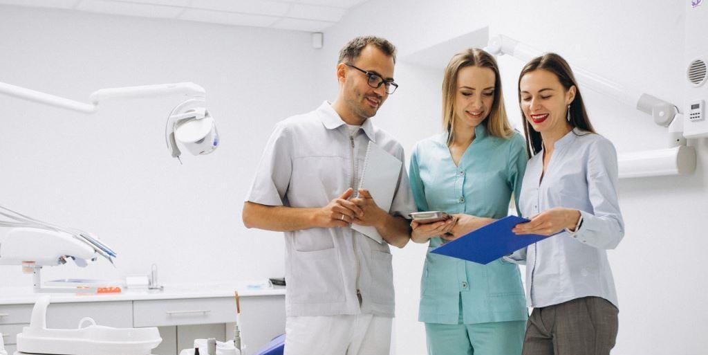 Three people discussing a clipboard in a dental practice